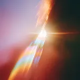 Abstract light streaks and lens flare with warm orange and cool blue tones on a dark background.