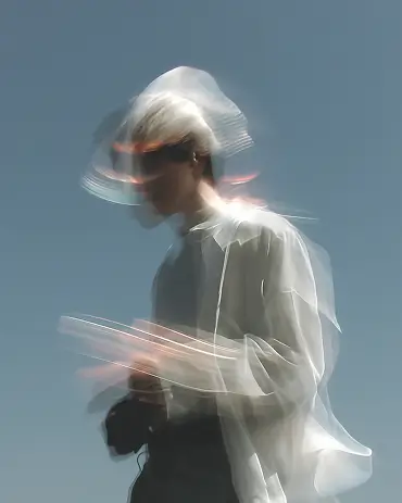 Blurred image of a person in motion wearing a light shirt against a clear sky background.