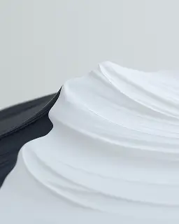 Close-up of smooth white cream or lotion on a dark surface with a light background.