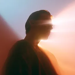 Silhouetted person with light beams crossing their face against a gradient blue and orange background.