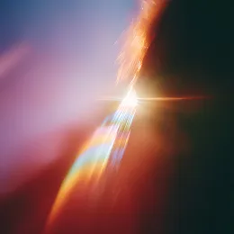 Abstract bright light with colorful lens flare and blurred background in red, orange, and purple hues.